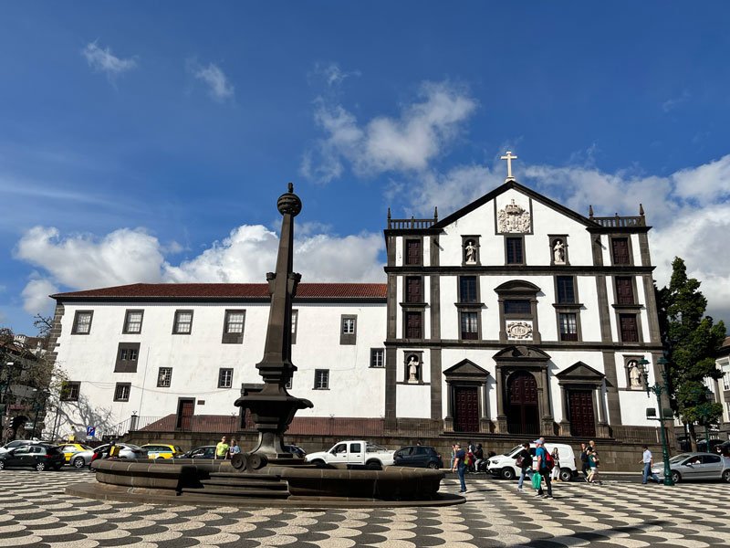 large whitewashed church with behind a mosaic patterened square