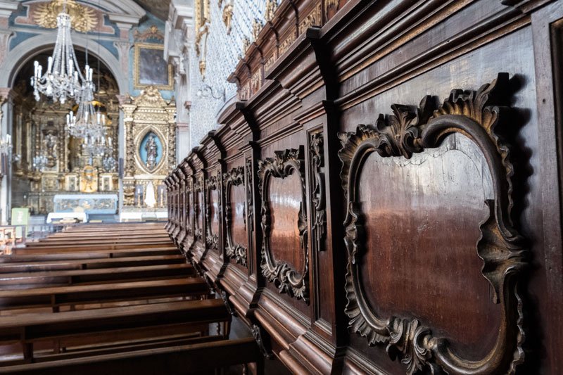 carved chior stalls in a church lined with blue and white tiles