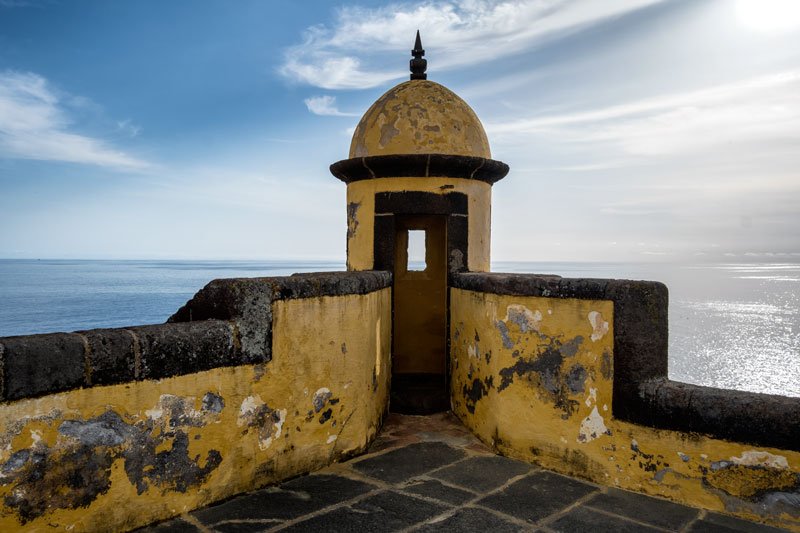 weatherbeaten yellow tower of fortress overlooking the ocean