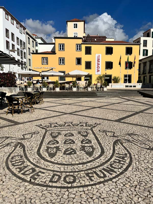 mosaic patterned square in front of a large yellow building in funchal in madeira