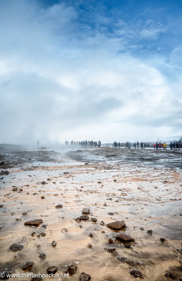 people walking through steaming lava field in geysir iceland