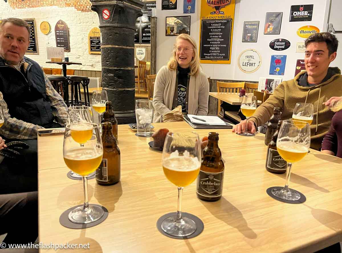 group of people sitting around table with belgian beers