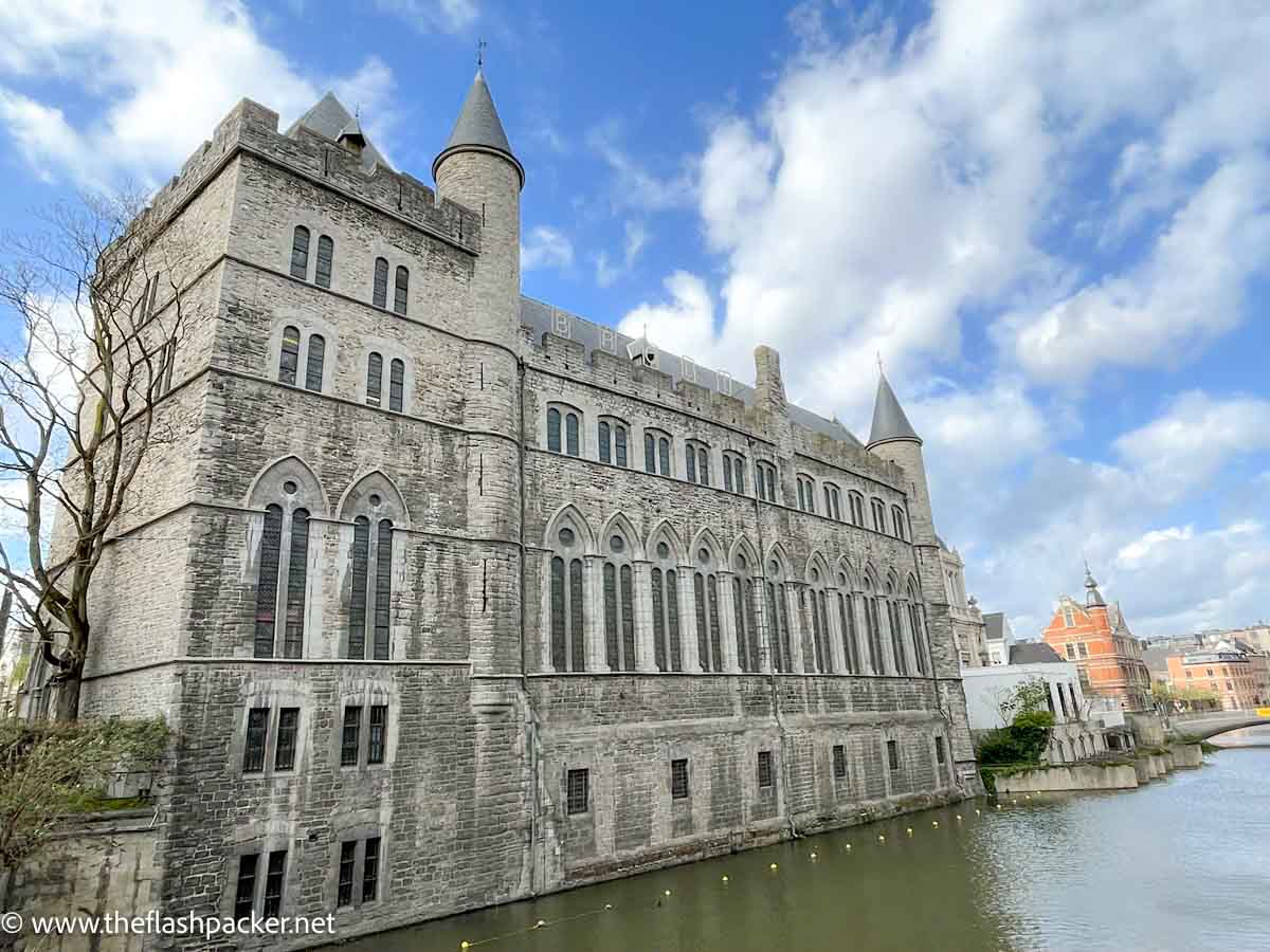 old grey stone turreted building by side of canal