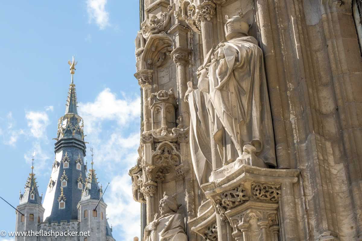 elaborate carved exterior of medieval building with spire in background