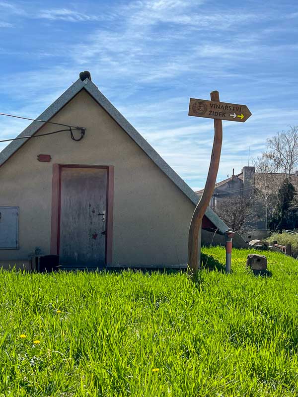 wooden signpost for zidek winery in front of simple building