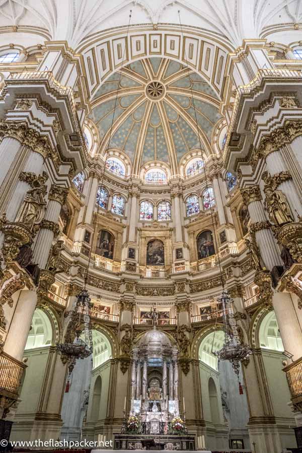 ornate interior of cathedral in granada with altar and tiered dome