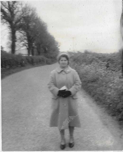 old woman standing in middle of country road