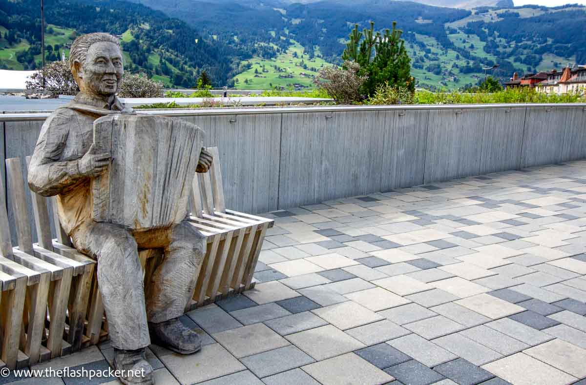 sculpture of man playing an accordion on a bench