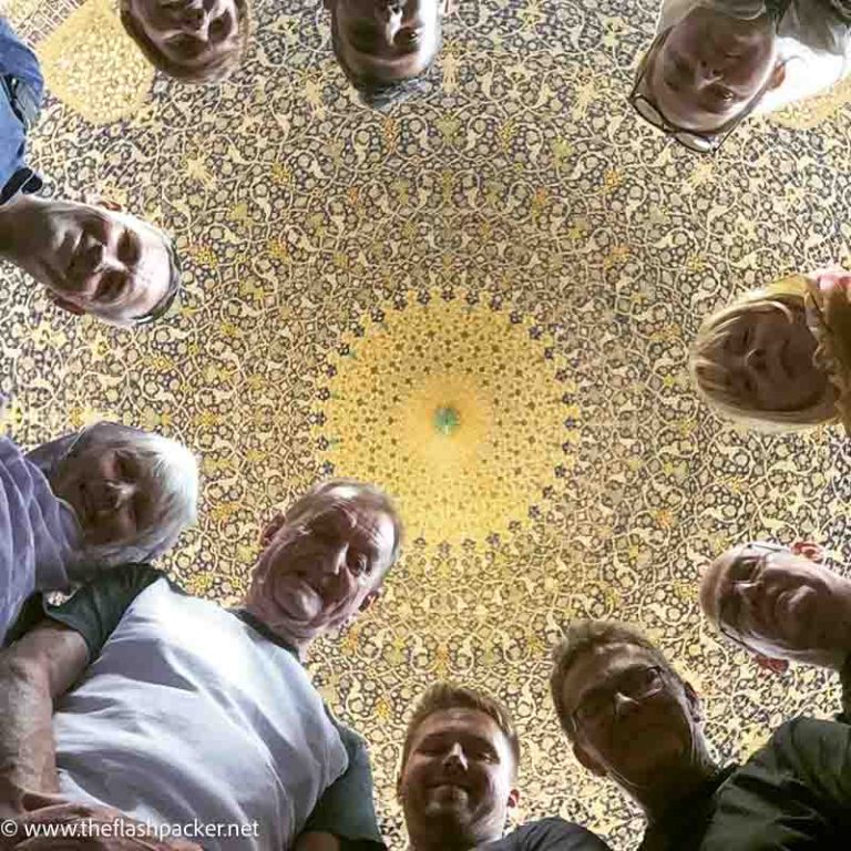 a group of people looking up at an interior dome of mosque