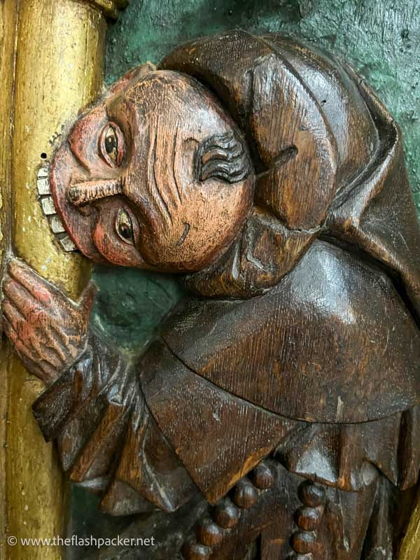 painted wooden carving of a man biting a pillar