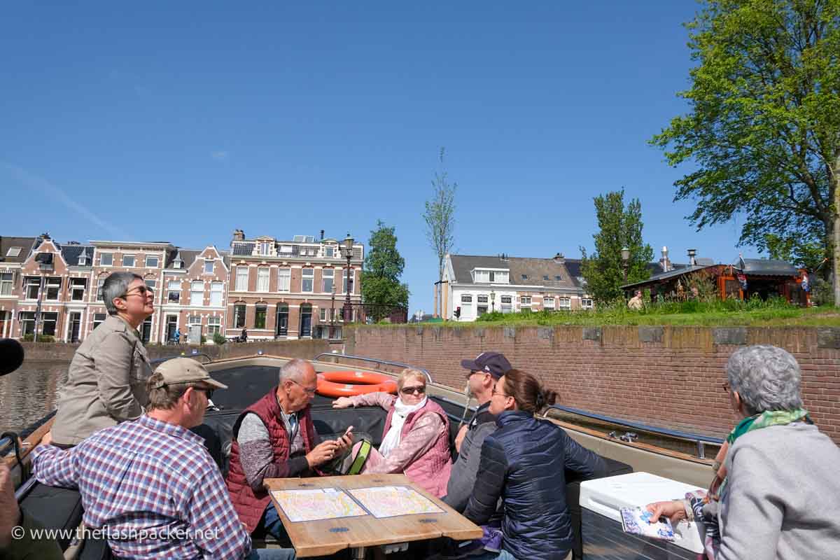 a group of tourists in a small open-top boat on a canal