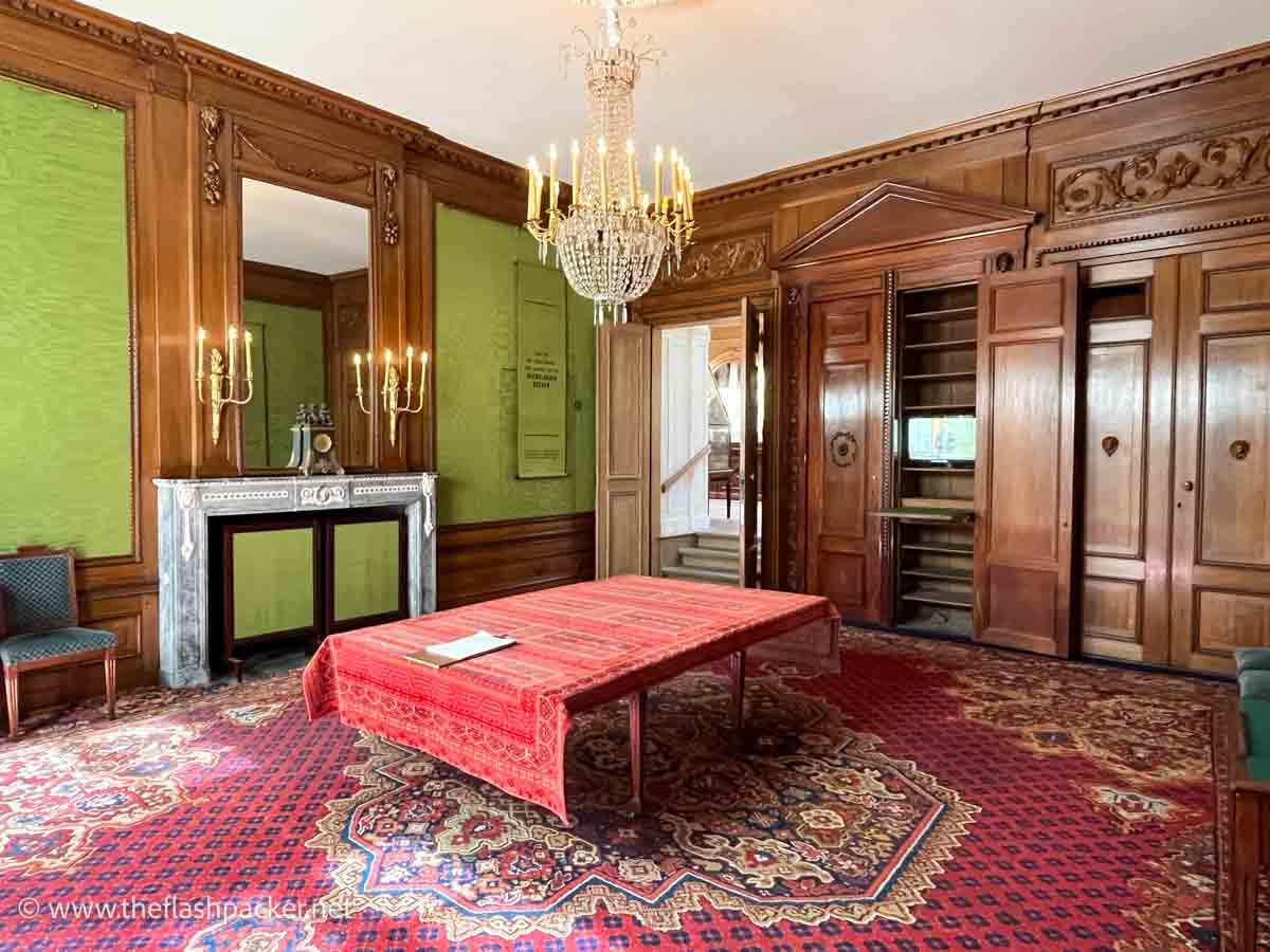 room with wooden panelling and a table with red cloth and chandelier