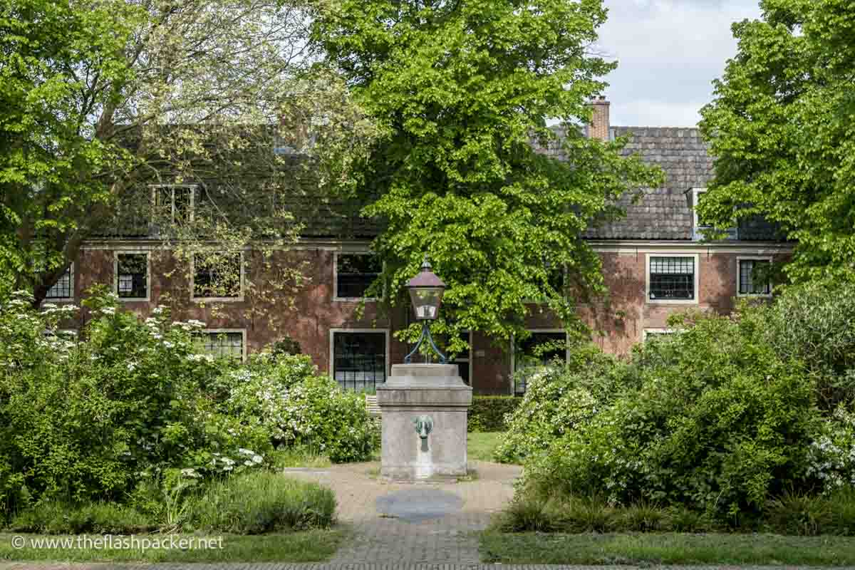 a lush courtyard in front of a row of almshouses