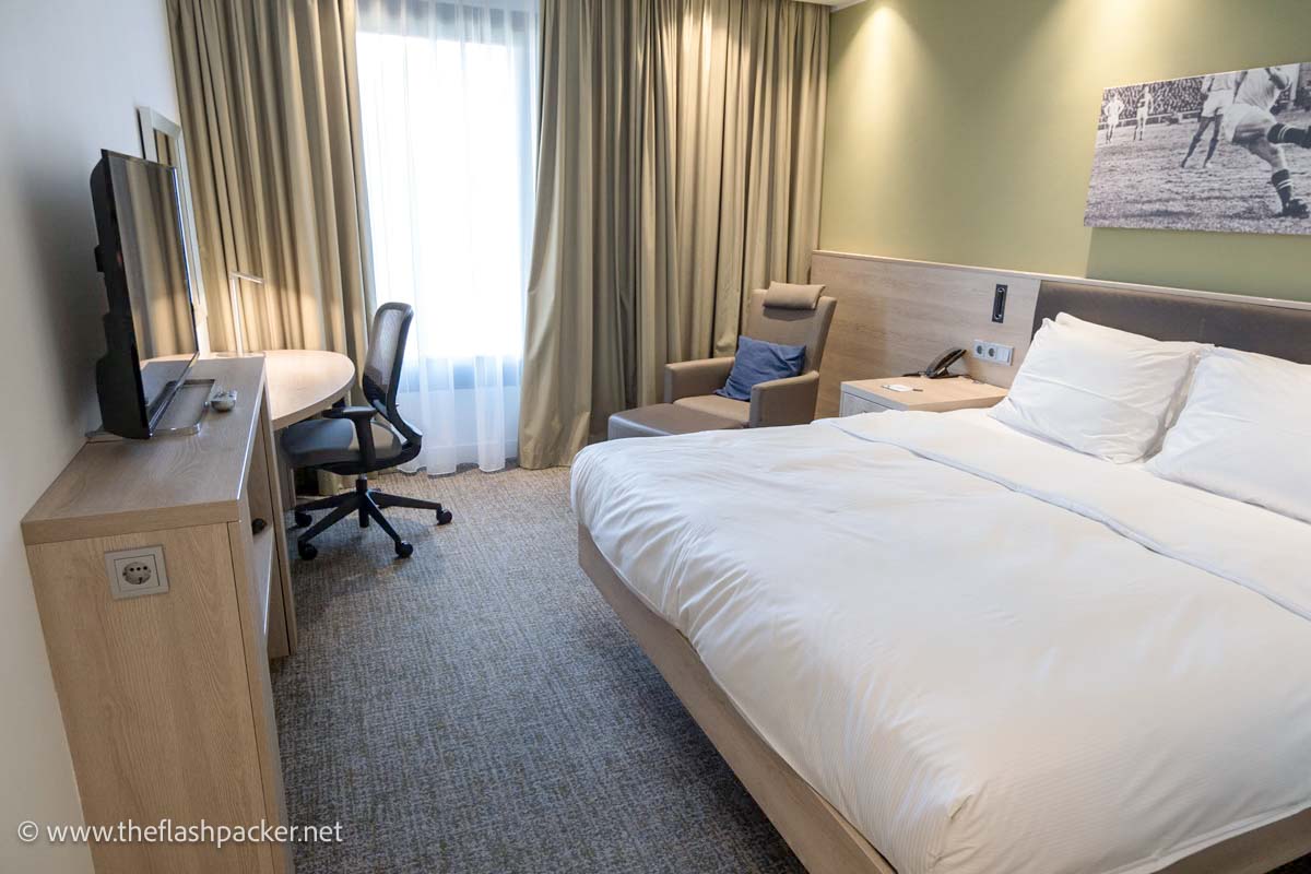 toom at hampton by hilton hotel in aachen with large bed with white linen, armchair table and chair and tv