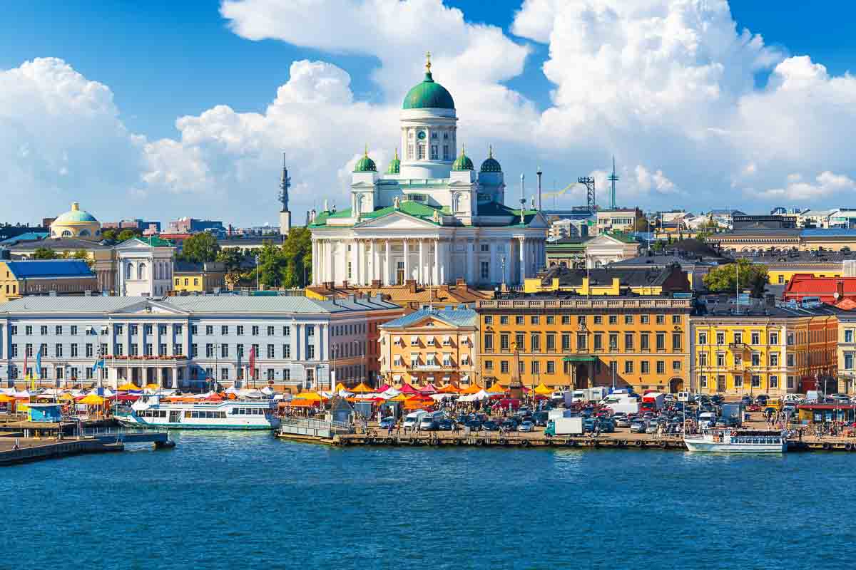 brightly colored buildings large white cathedral and boats along the seafront in helsinki finland