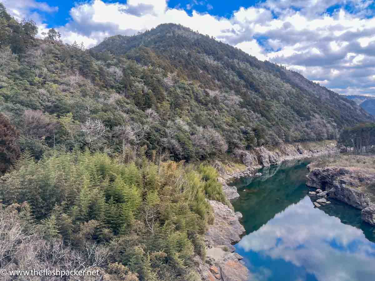 a glacial mountain stream with reflections of clouds and hillside