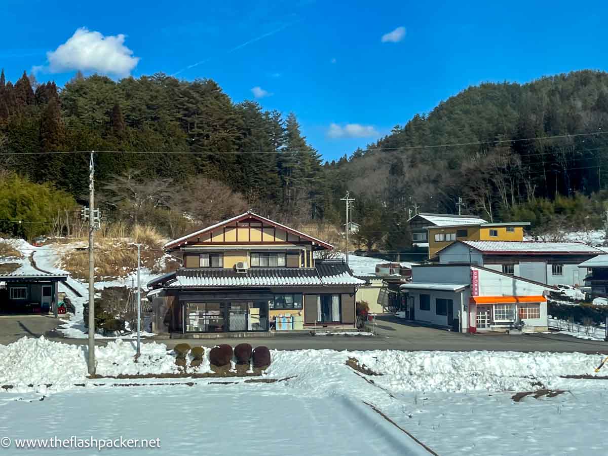 a small settlement of japanese houses by the side of a snow covered railway track