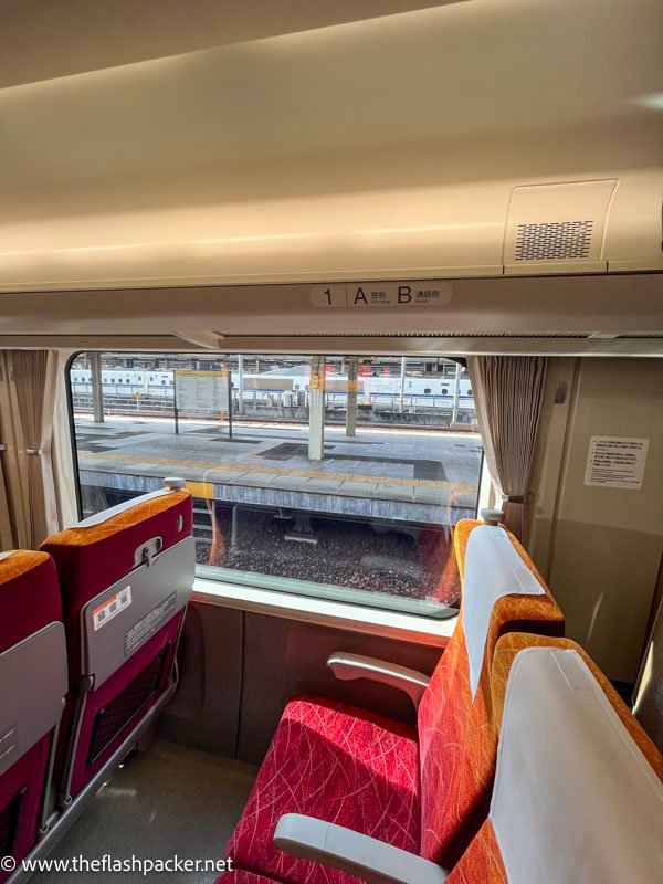 red-orange seats with grey armrests in a carriage on the wide hida limited express train