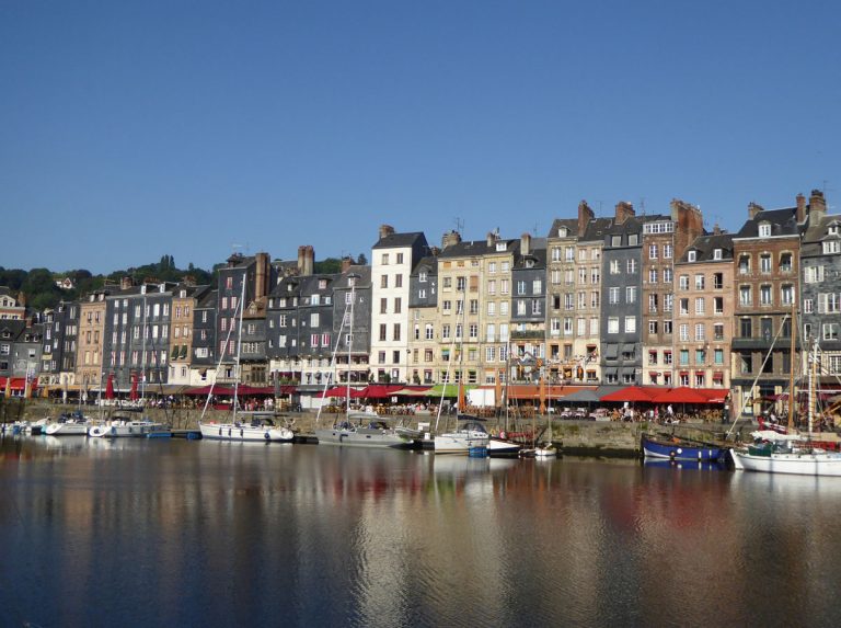 brightly coloured houses of honfleur normandy reflected in the water of the harbour