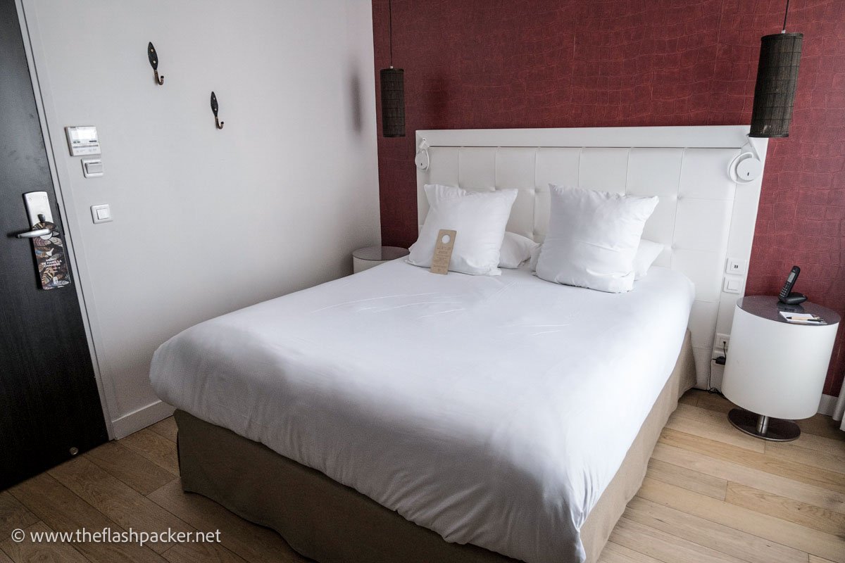 hotel bedroom in lille with double bed with white linen and circular bedside table