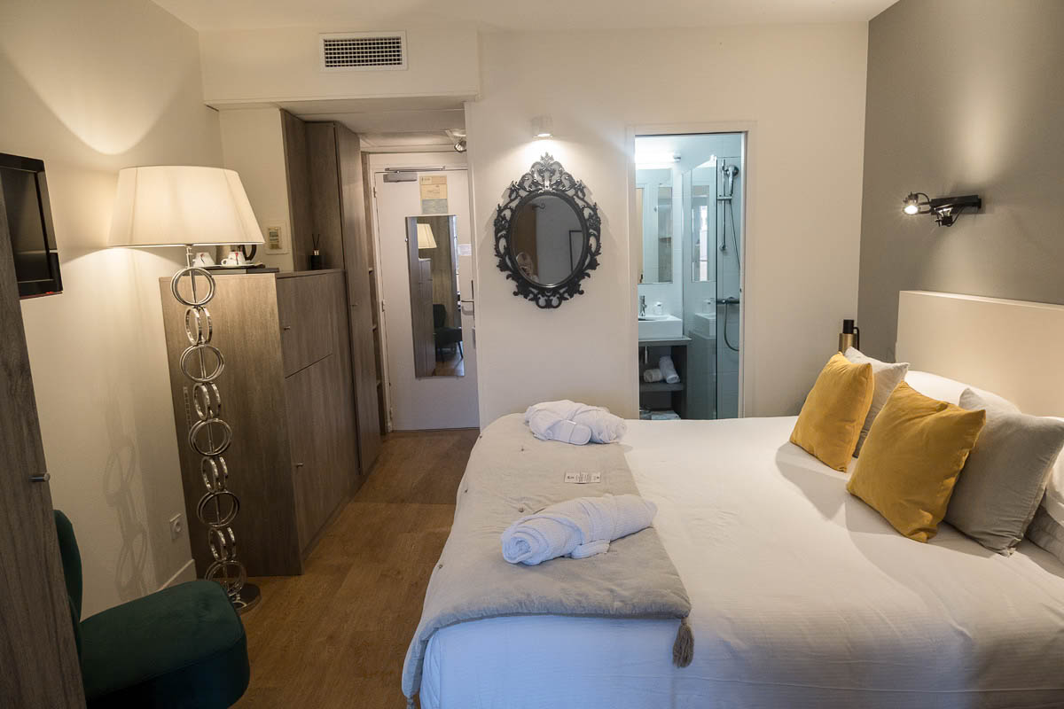 room at hotel madeloc in collioure with large bed with yellow cushions and bathroom entrance