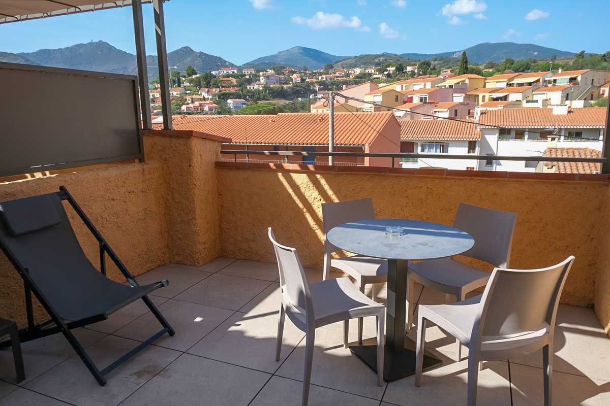 room terrace at hotel madeloc collioure with table and chairs and view of distant mountains