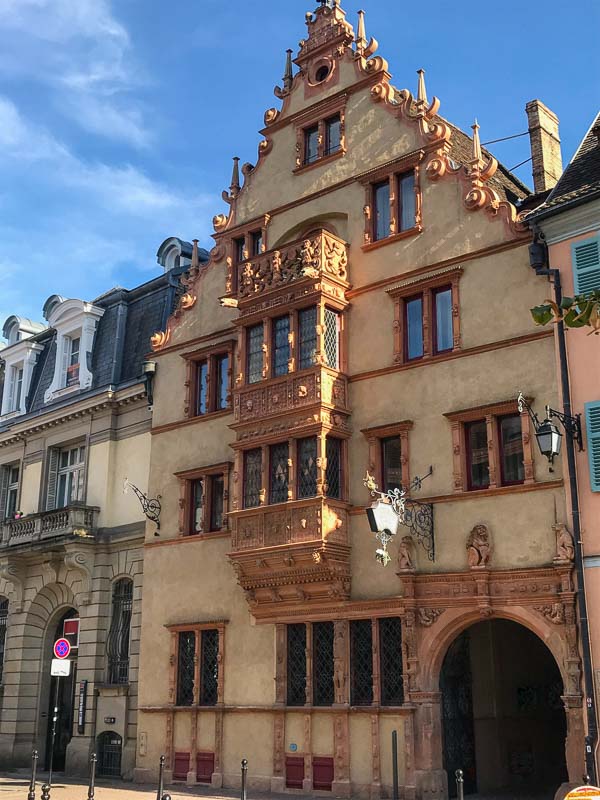 tall gabled building adorned with wooden windows with carvings of heads