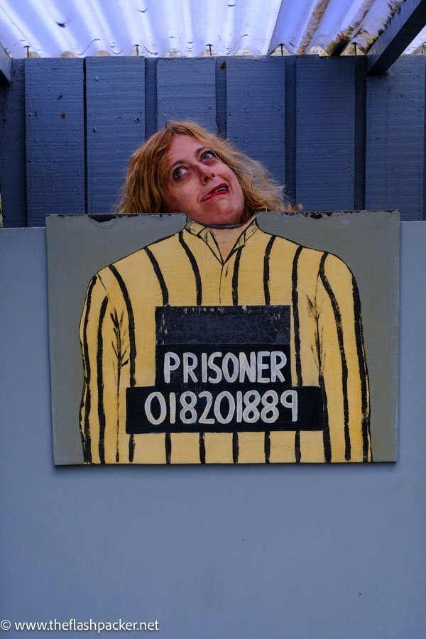 woman grimacing against a cut out of a prisoners uniform