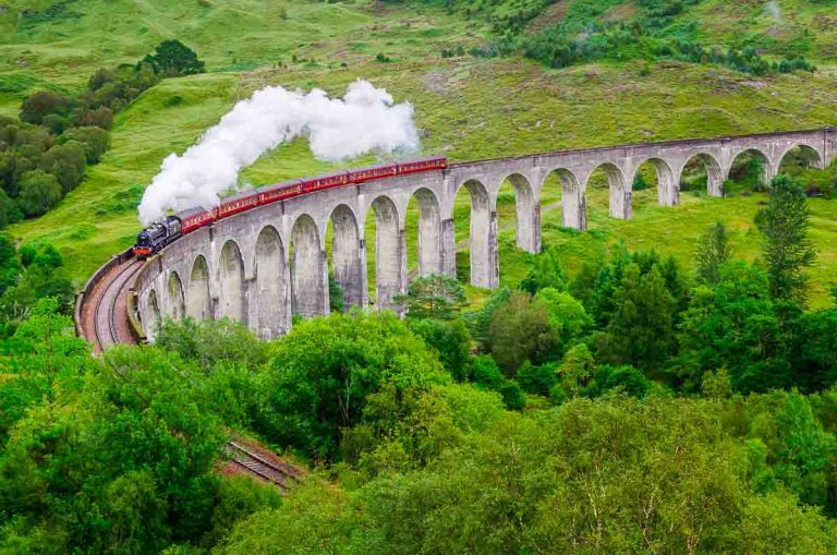 the jacobite steam train going over a curved viaduct known as the harry potter bridge