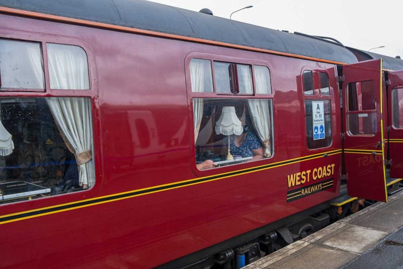 red exterior of jacobite steam train looking into 1st class carriage