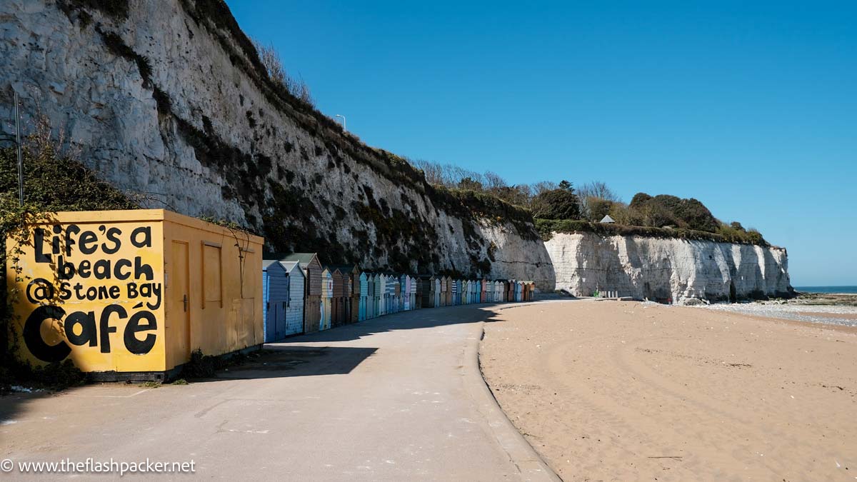 row of beach huts against a cliff on a sandy kent beach in england