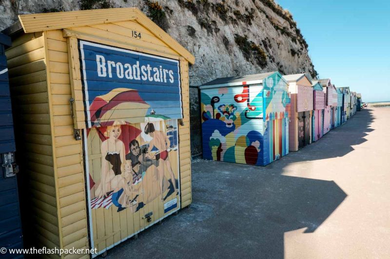 row of brightly painted beach huts on a sandy beach