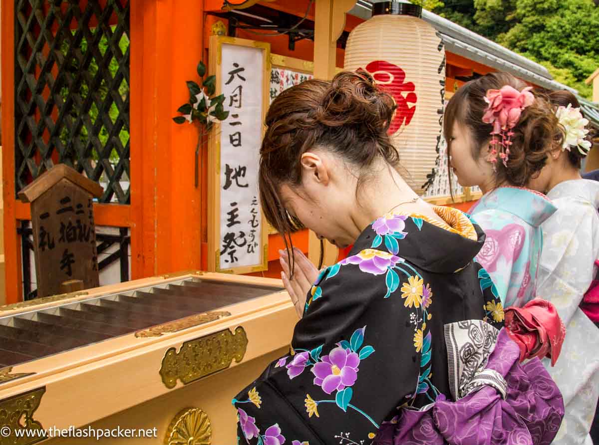 women dressed in kimonos praying at shrine at Kiyomizu-dera in kyoto japan