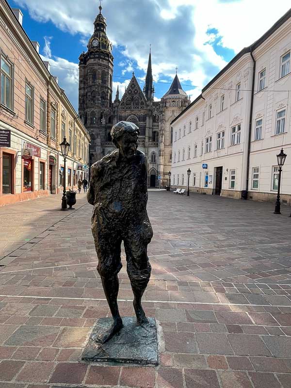 bronze sculpture of a man with the cathedral in kosice in background