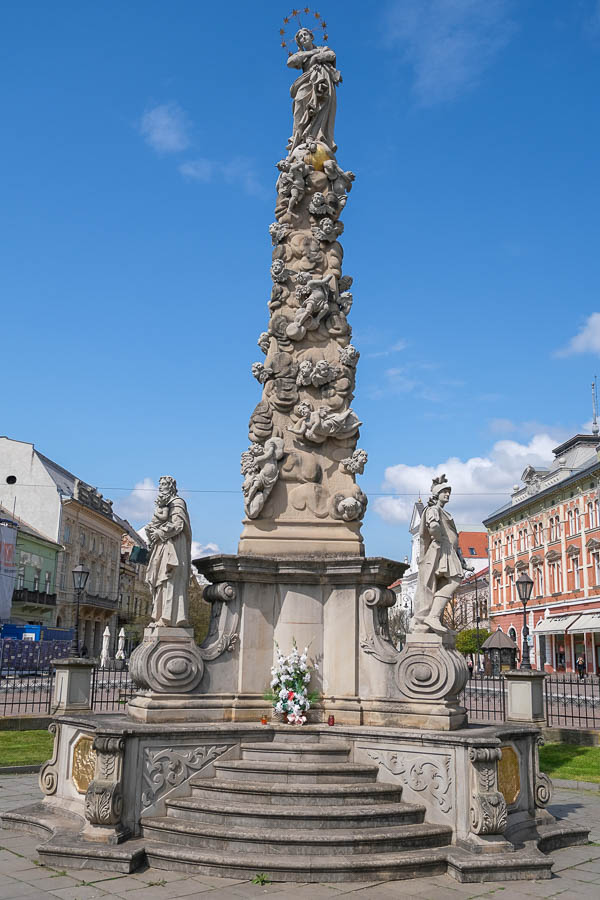 ornately carved stone column with virgin mary with crown on the top