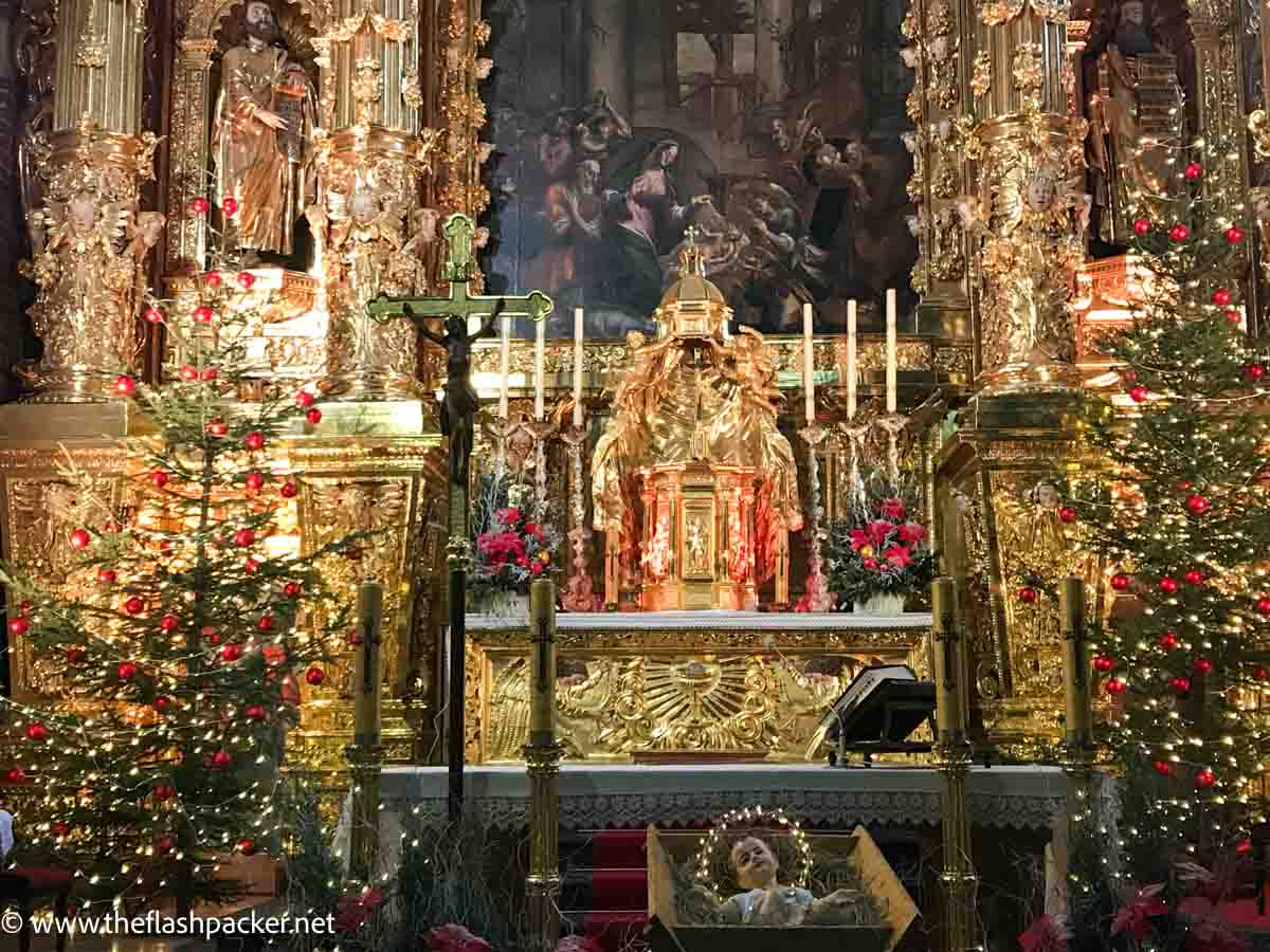 gilded church altar with xmas decorations and crib