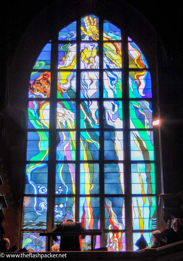 choirmaster conducting in front of a stained glass window