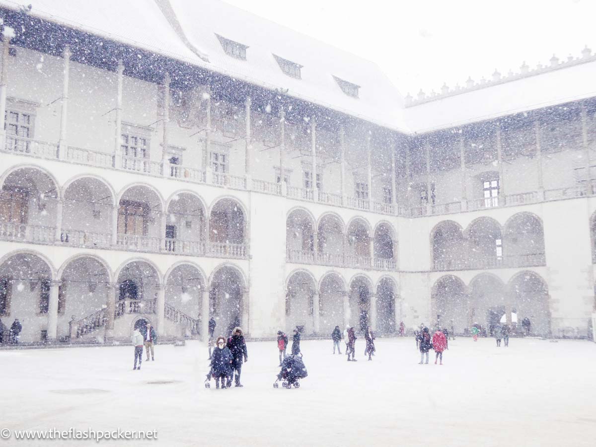 people walking in snow in castle courtyard in krakow poland