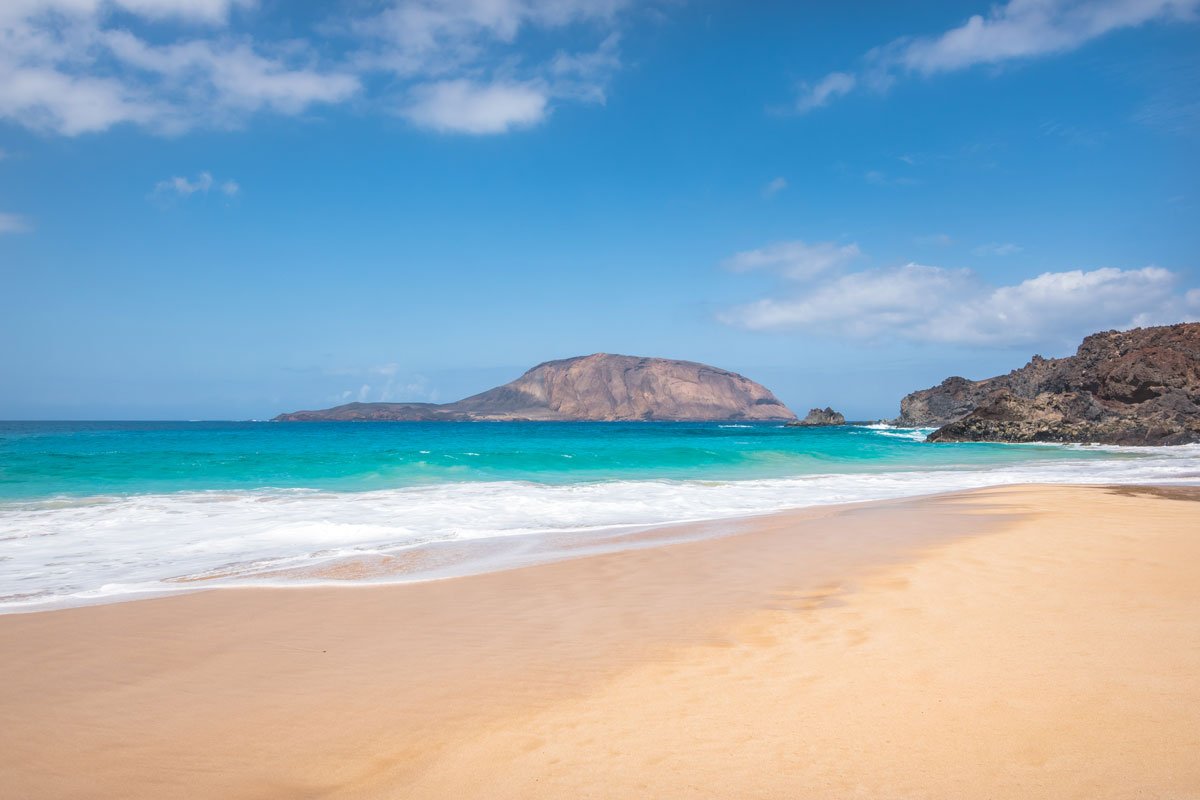 beautiful sandy beach with mounds in distance