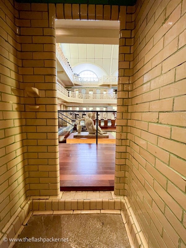 tiled changing cubicle looking out onto an old art deco swimming pool converted into an art gallery