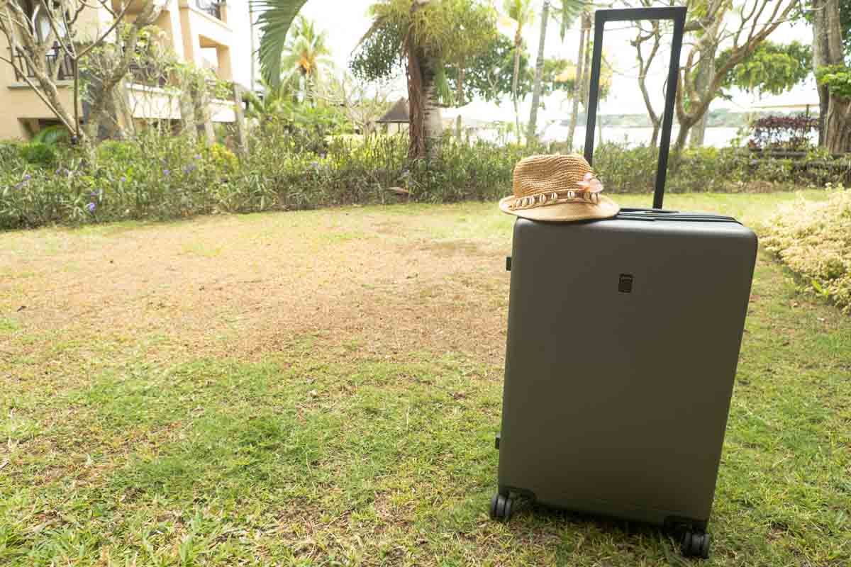 straw hat on top of a great suitcase in the garden of a luxury hotel