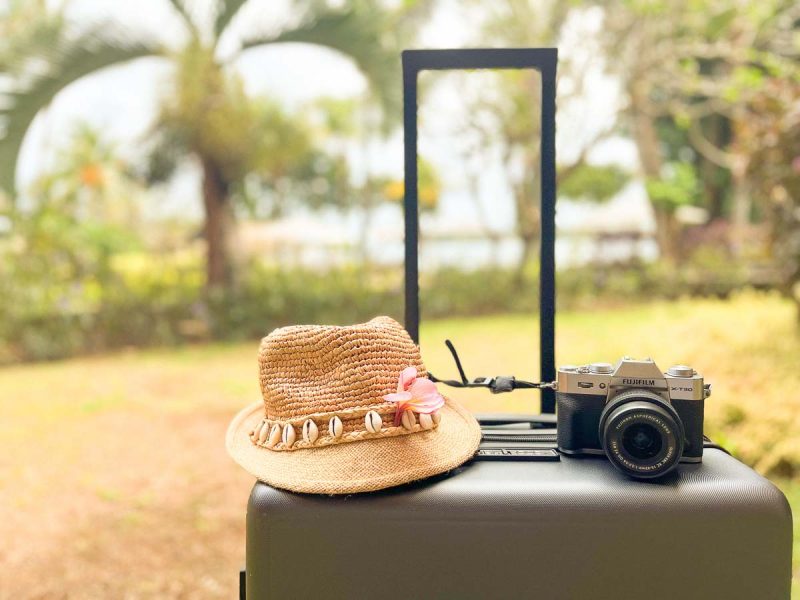 camera and straw hat on top of LEVEL8 suitcase