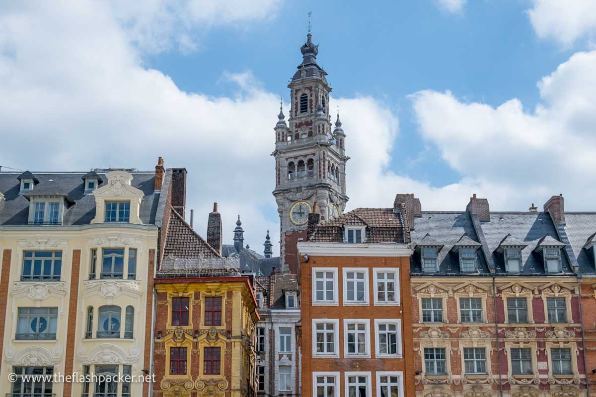 colourful facades of tall flemish houses in Lille old town in front of church bell tower