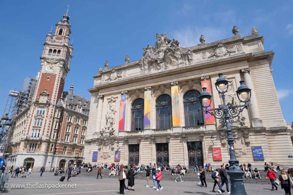 people walking past the flamboyant white baroque exterior of lille opera house