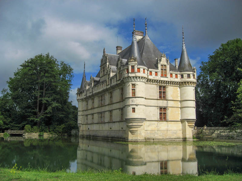 exterior of turreted chateau with reflection in small lake in the loire valley