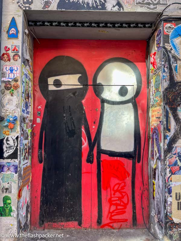 painting on a doorway of 2 stick figures holding hands