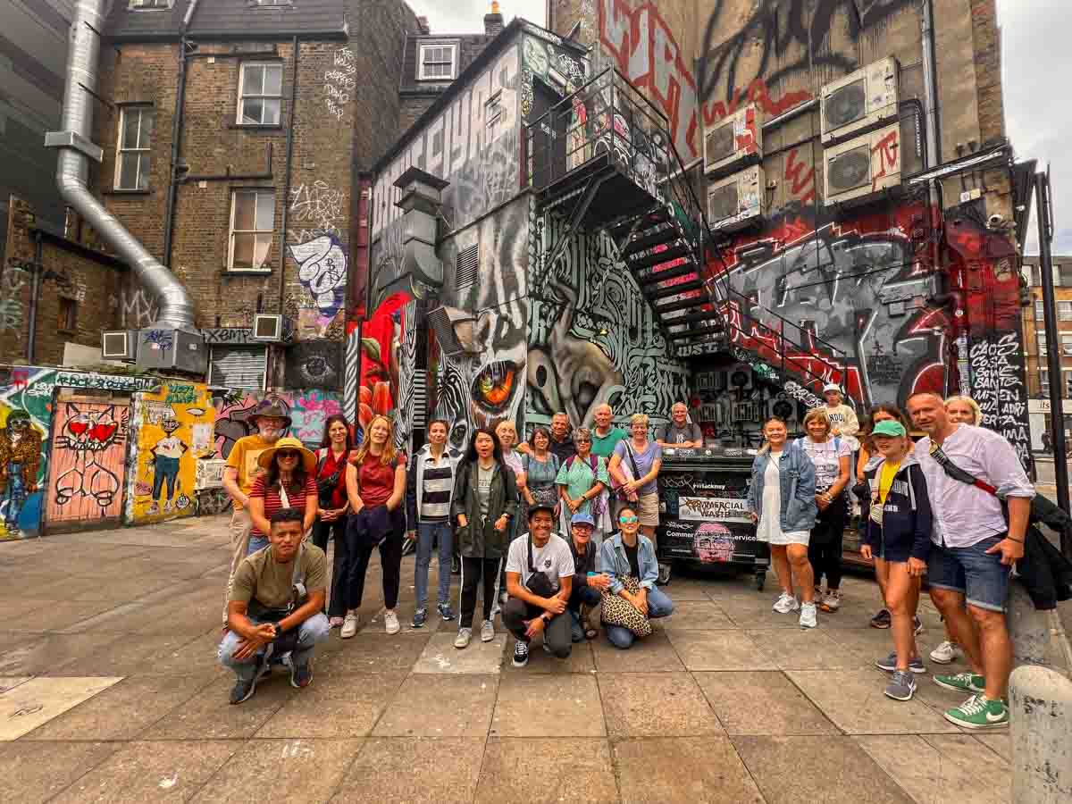 group of people on a london street art walking tour gathered in front of murals and graffiti in shoreditch