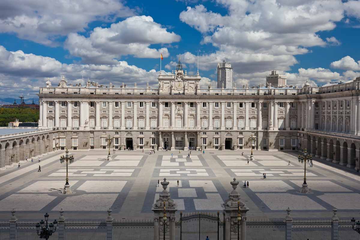 exterior of wide facade of madrid royal palace behind a rectangular courtyard