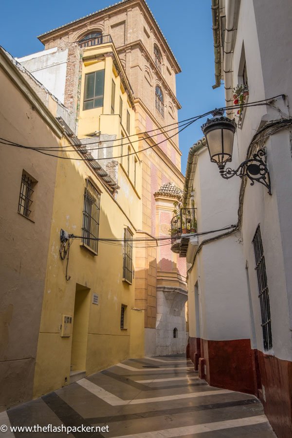 beige ochre and salmon pink houses lining narrow street in malaga spain