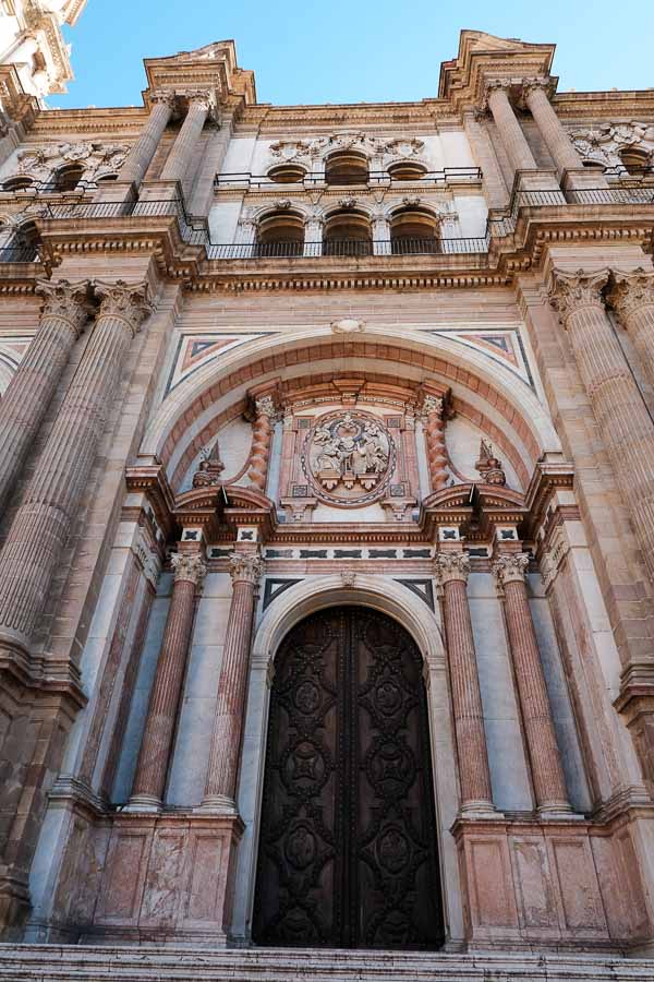 the magnificent main entrance to malaga cathedral with arched doorway and pinkish columns